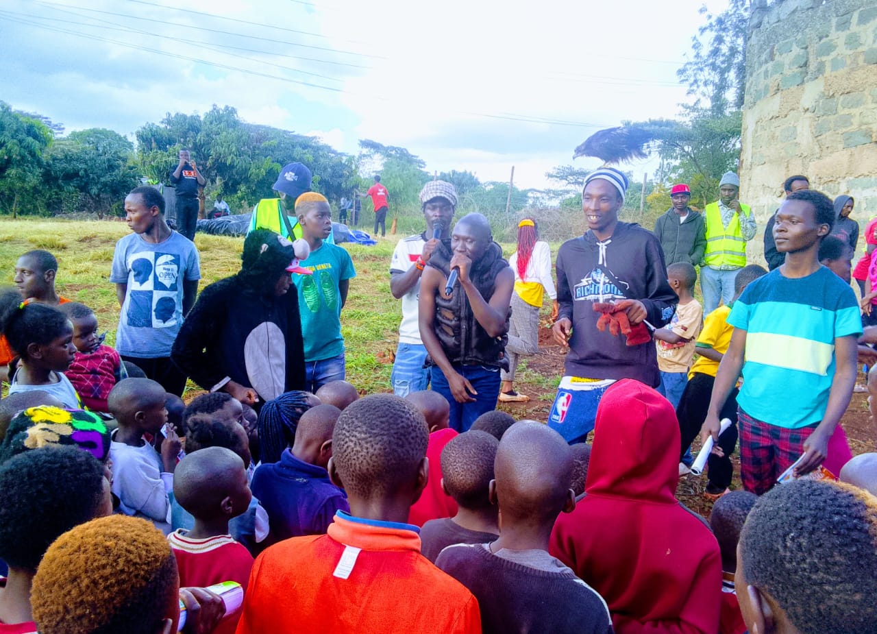 Thee Joint performing to a crowd of children at an outreach event
