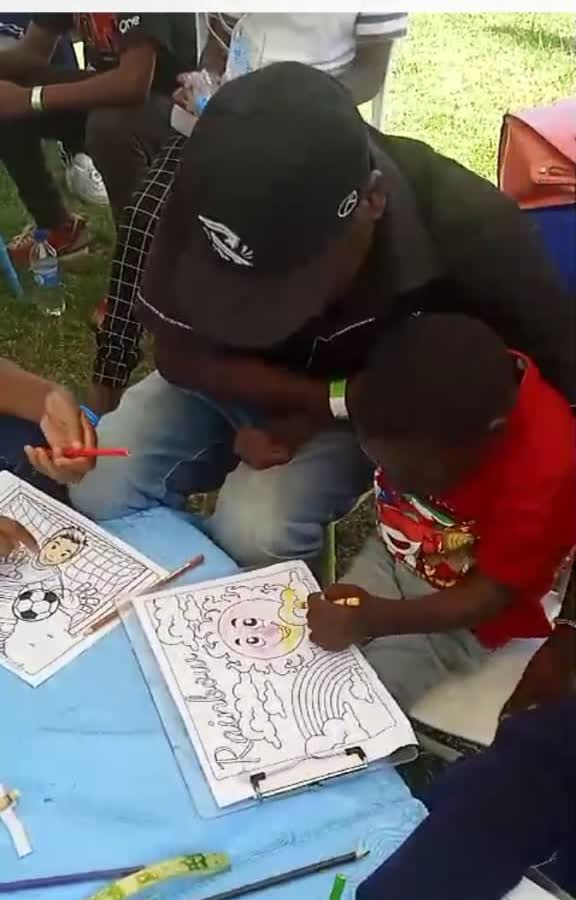 A mentor helping a child colour a drawing at a G4G workshop